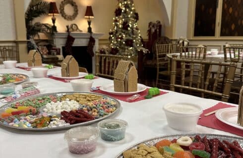 Group of adults and kids in a dining room making gingerbread houses