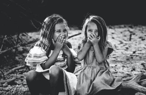 Black and white photograph of two girls sitting and giggling