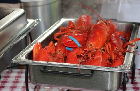 Silver warming dish filled with bright red cooked lobster