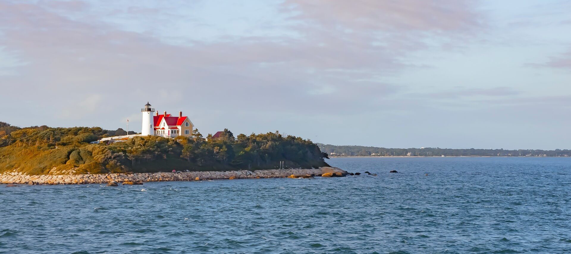 A red and white lighthouse building on a peninsula surrounded by water