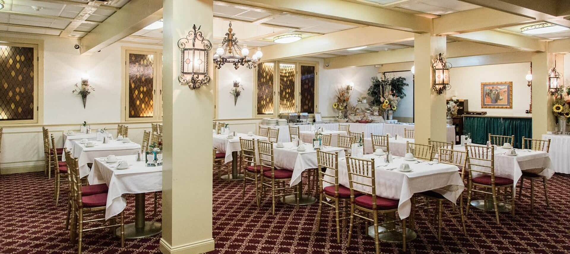 Elegant dining room with tables set in white with gold and red chairs