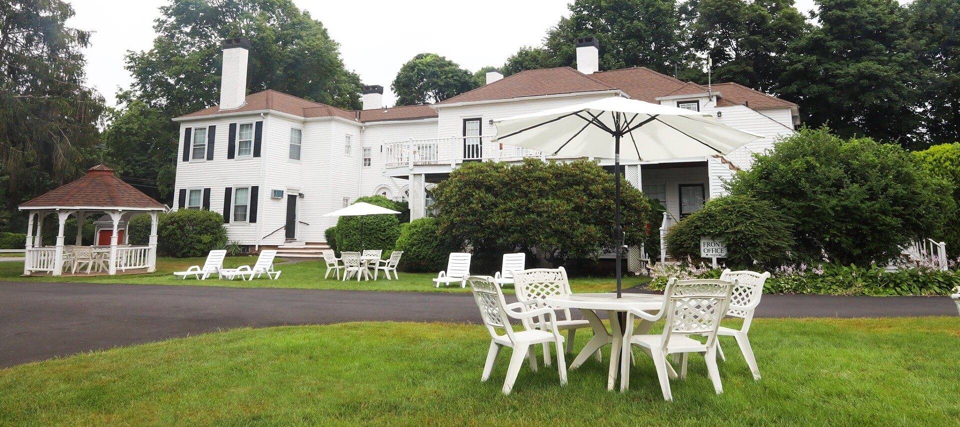 Outdoor lawn area in front of a large white building with patio tables and lounging chairs